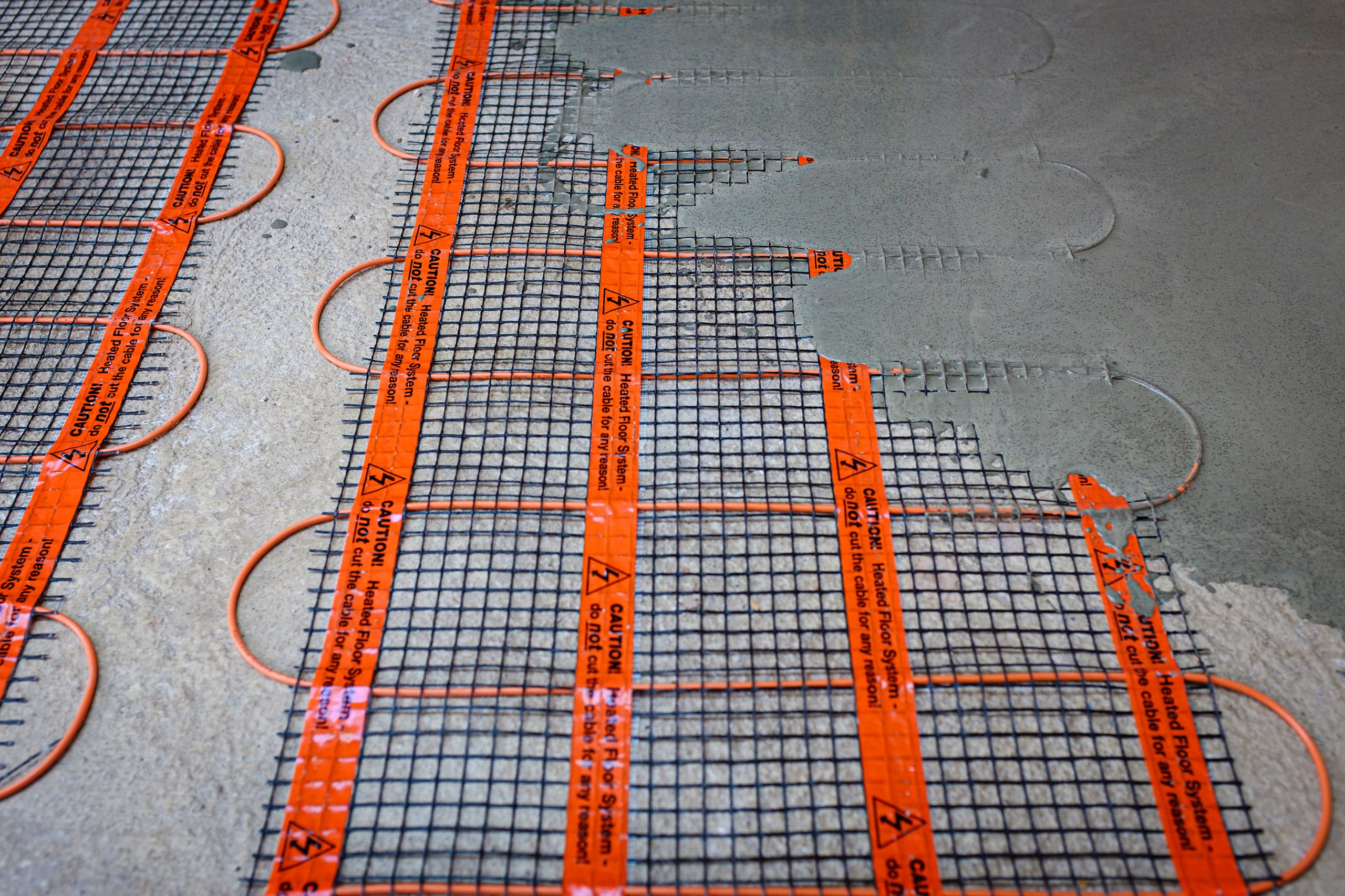 Installierte, elektrische Fußbodenheizung mit sichtbarem, leitfähigem Gitter. Das Betonieren der darüberliegenden Estrichfläche hat bereits begonnen.