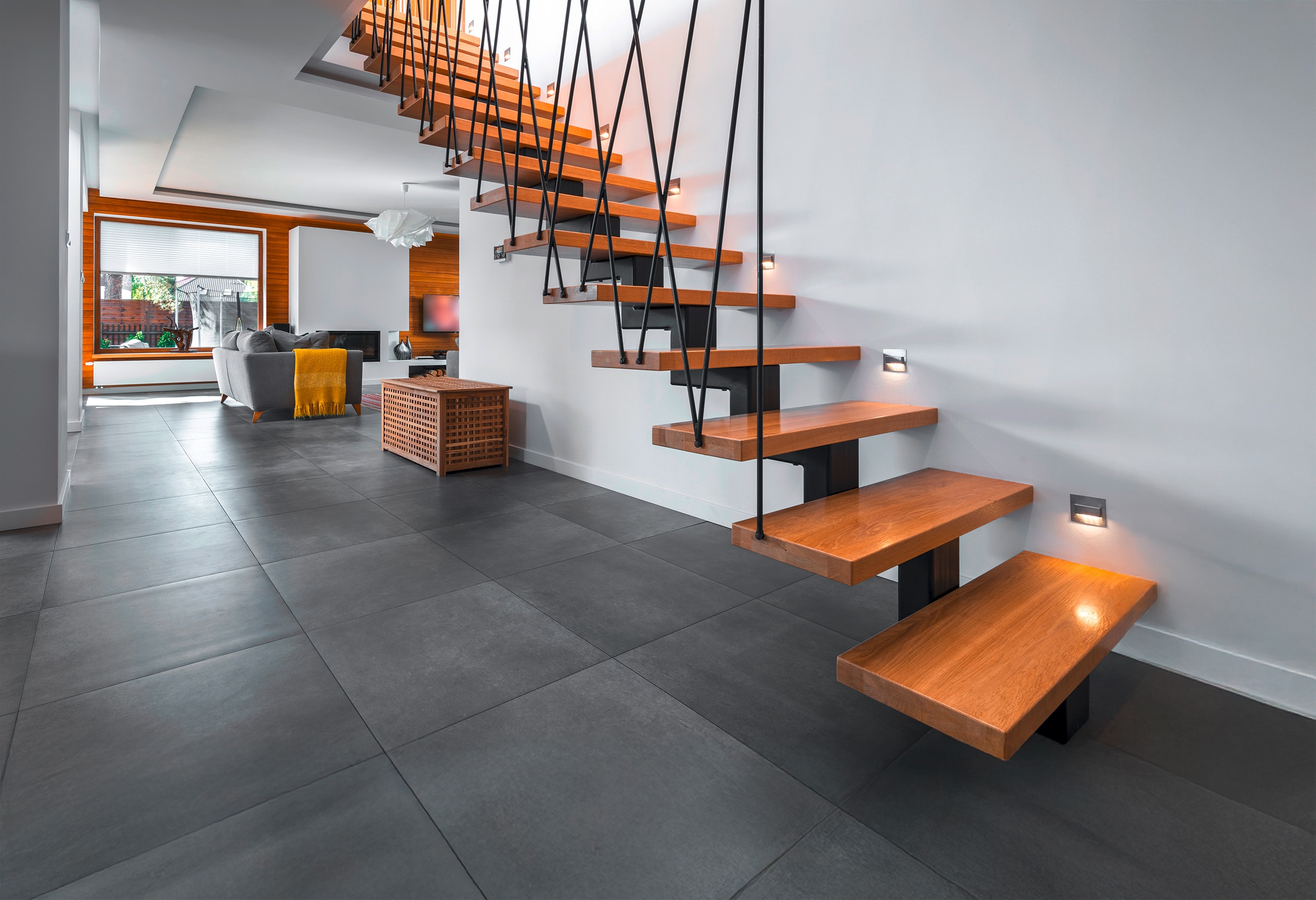 Moderne Metalltreppe mit Trittstufen aus Holz und extravagantem Geländer aus schwarzen, diagonalen Metallrohren.