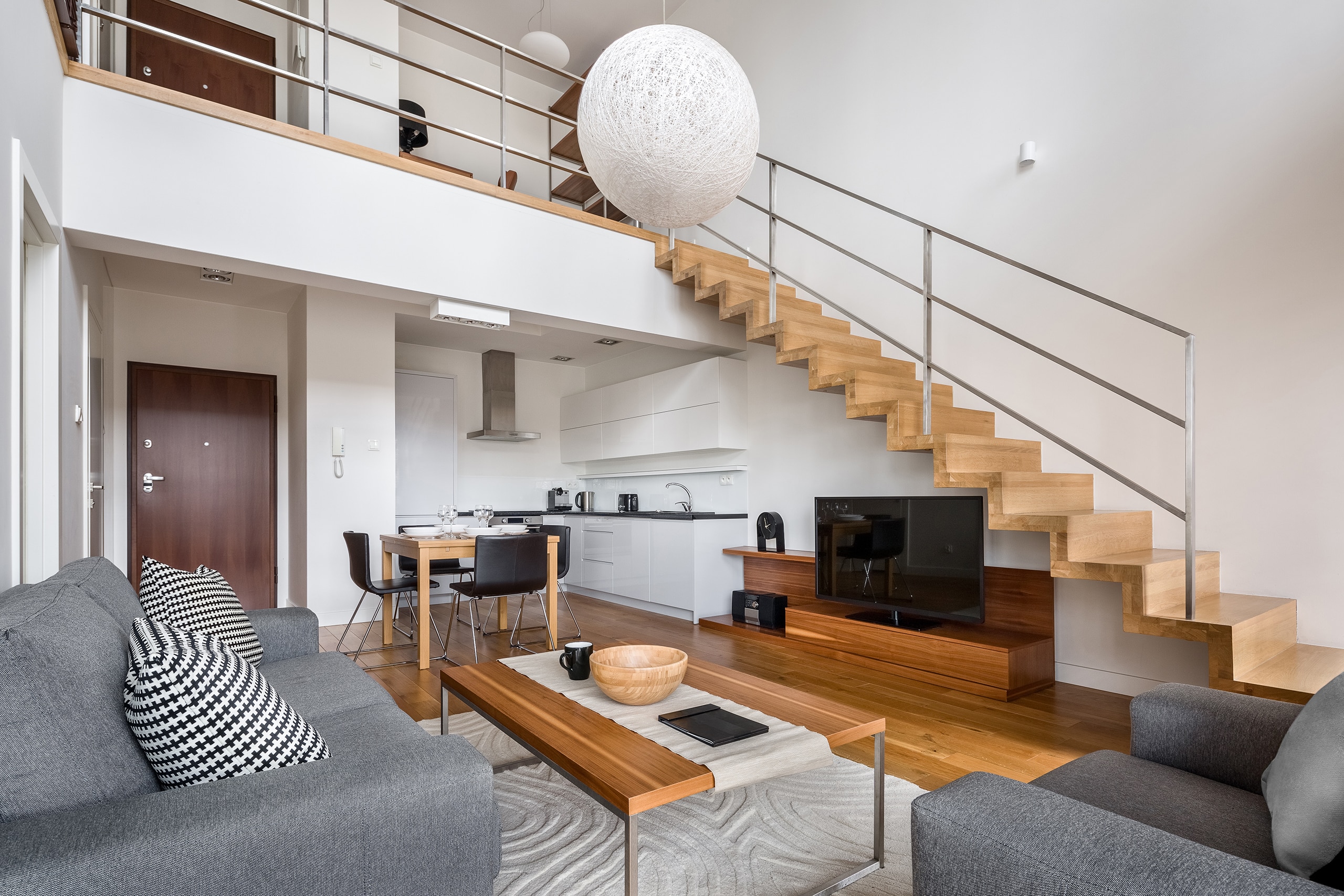 Modernes Appartement mit Maisonette, die über eine geradlinige Holztreppte mit Edelstahlgeländer erreicht wird.