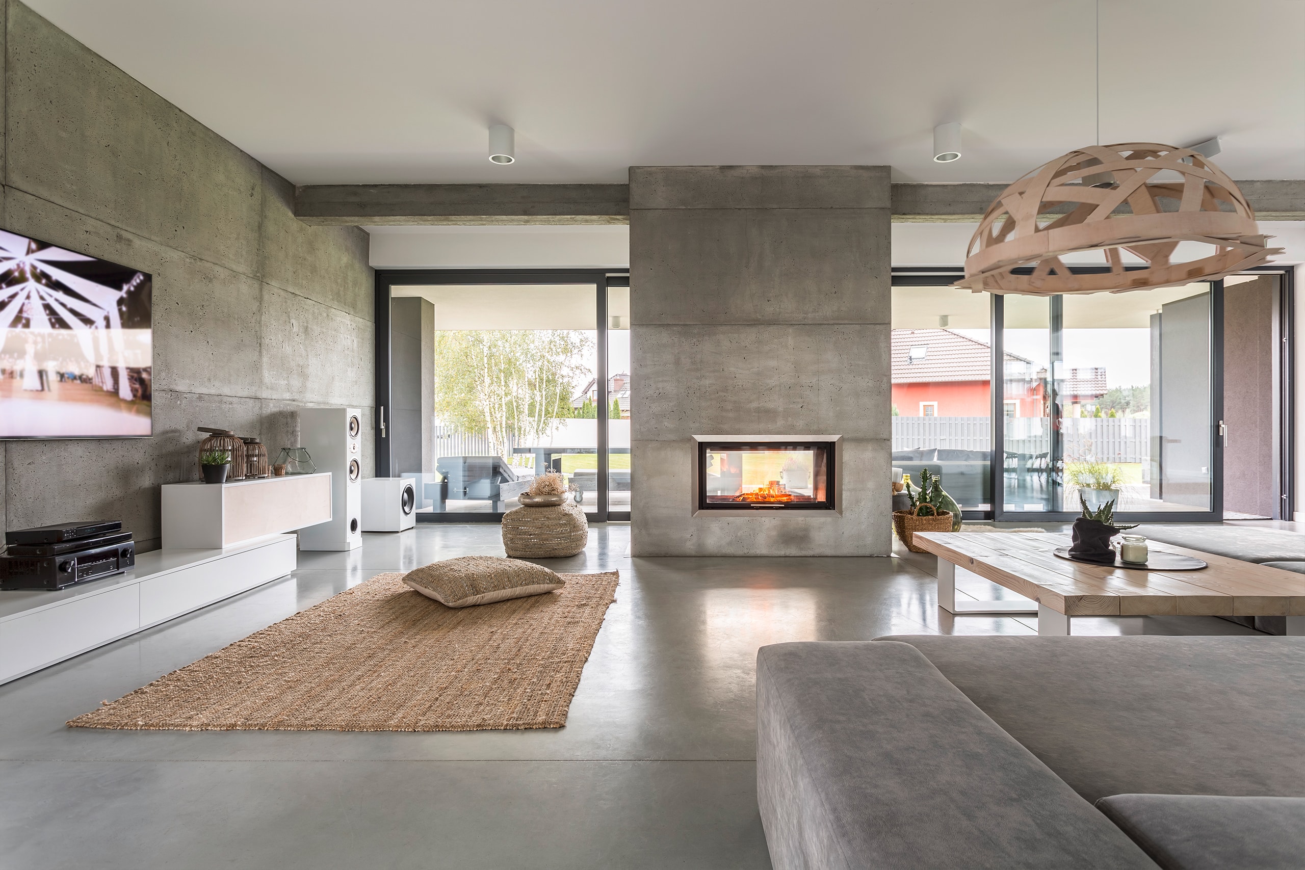 Großzügige, moderne Villa mit freistehendem Kamin im Betonlook im Wohnraum.