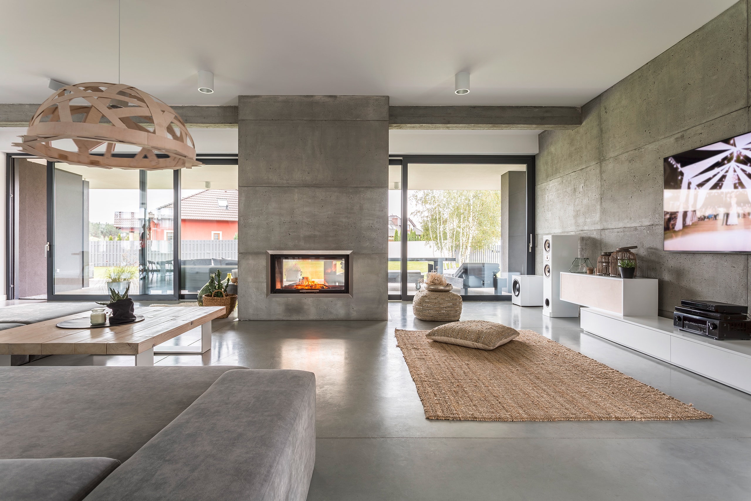 Großzügige, moderne Villa mit freistehendem Kamin im Betonlook im Wohnraum.