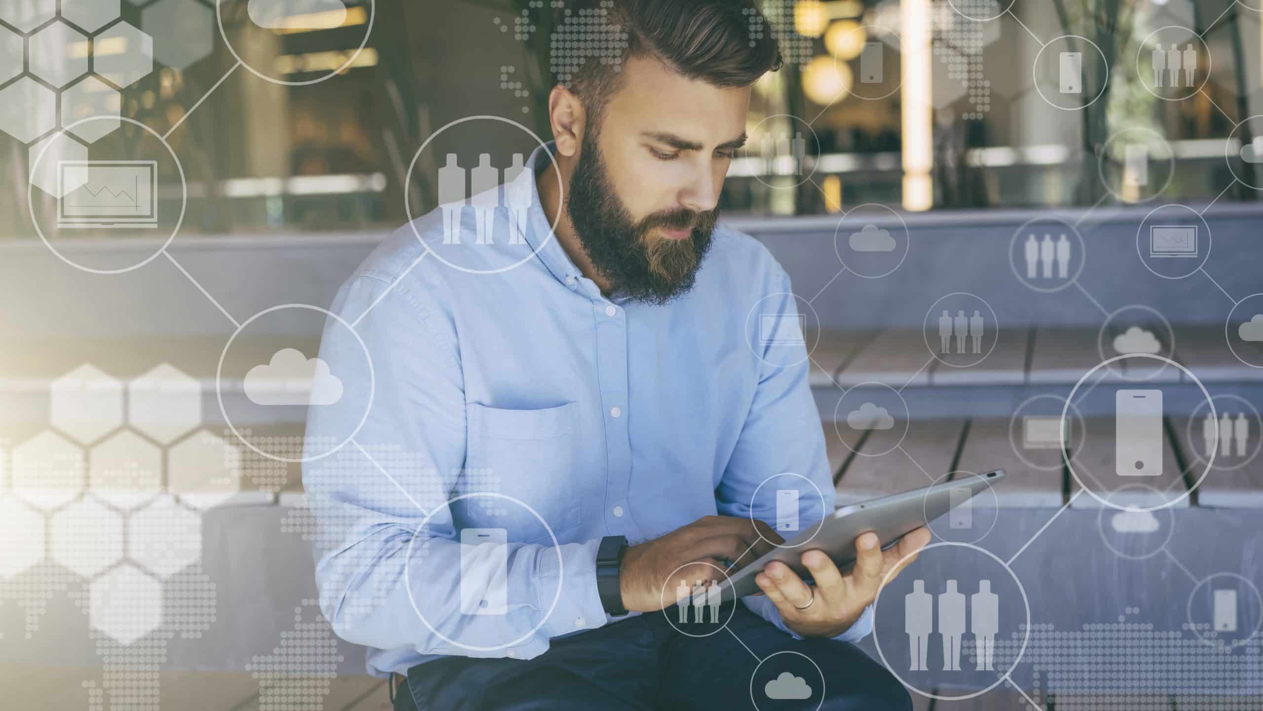Businessmann arbeitet am Tablet sitzend auf den Stufen eines Firmengebäudes.